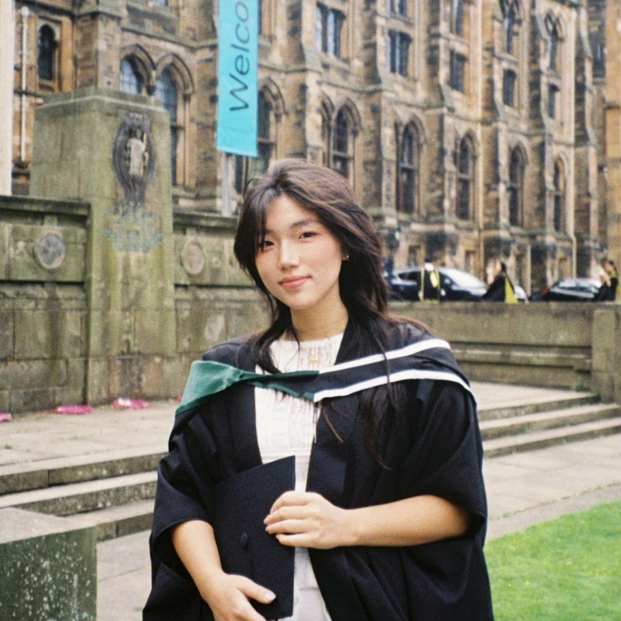 刘奕菲身着毕业礼服，站在校园建筑前